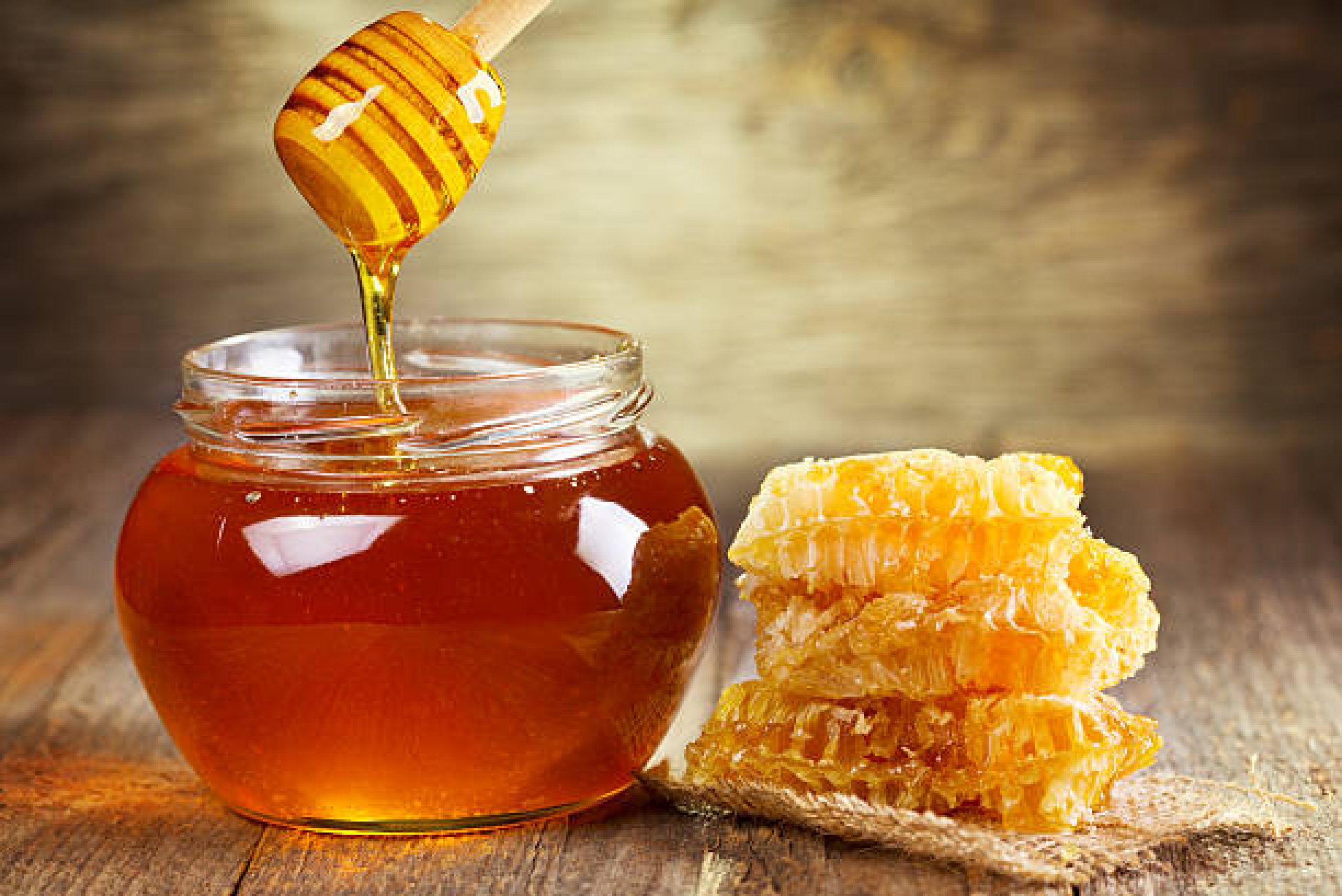 jar of honey with honeycomb on wooden table